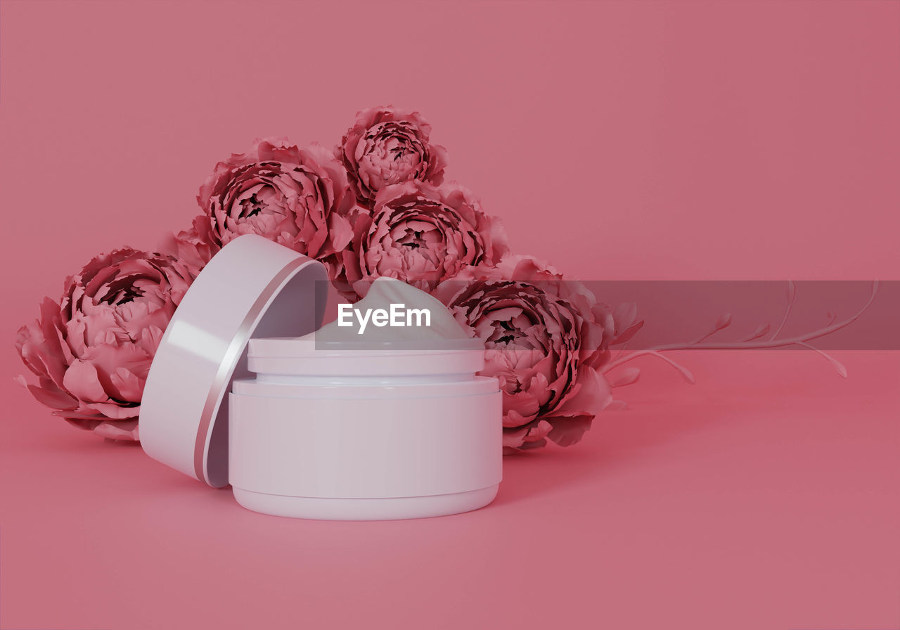 CLOSE-UP OF PINK ROSE FLOWER ON TABLE AGAINST RED BACKGROUND