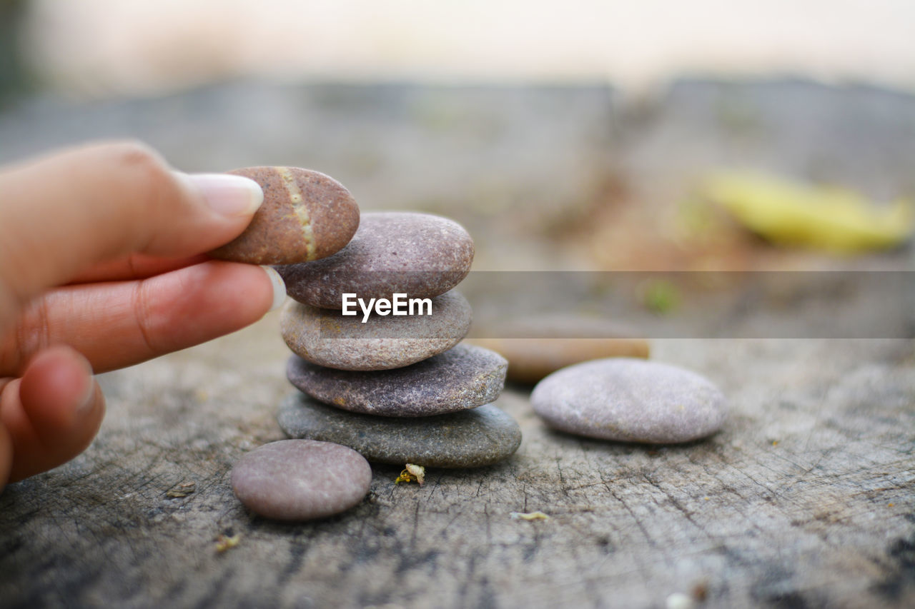 Cropped hand of person stacking pebble stones