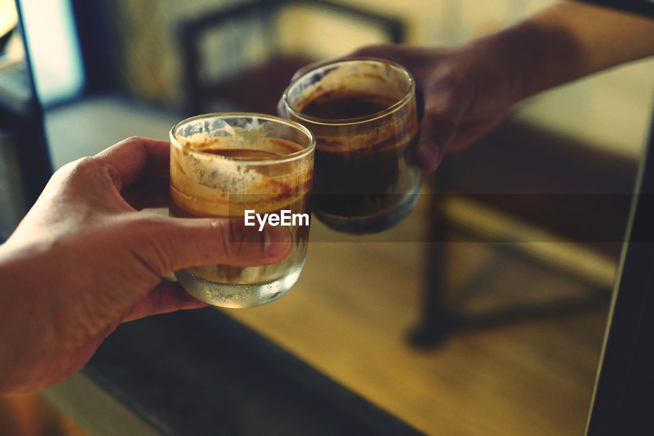 Cropped hand of person holding drink against mirror