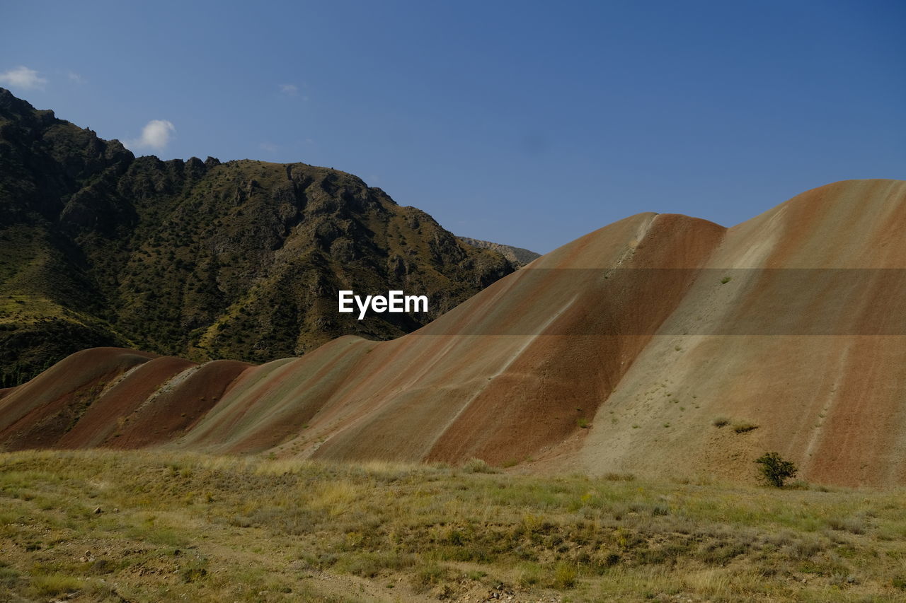 landscape, environment, land, scenics - nature, hill, sky, nature, natural environment, wilderness, beauty in nature, no people, non-urban scene, plant, plateau, valley, travel destinations, geology, travel, blue, ridge, tranquility, grass, desert, outdoors, mountain range, day, clear sky, soil, grassland, tranquil scene, rock, terrain, sunny, tourism