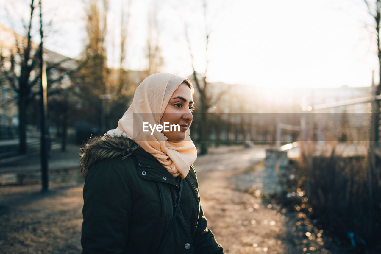 Young muslim woman wearing hijab in city during sunset