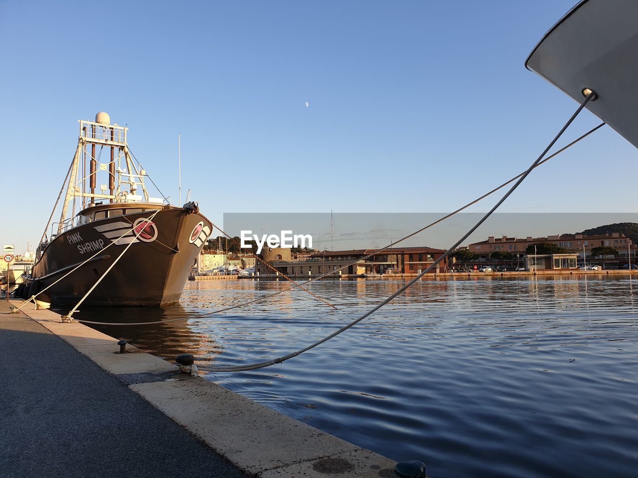 SAILBOATS MOORED IN SEA AGAINST CLEAR SKY