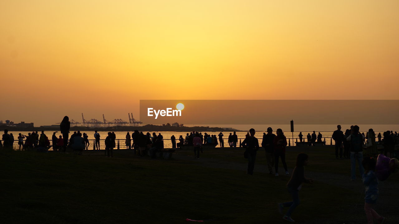 Silhouette people at beach against sky during sunset