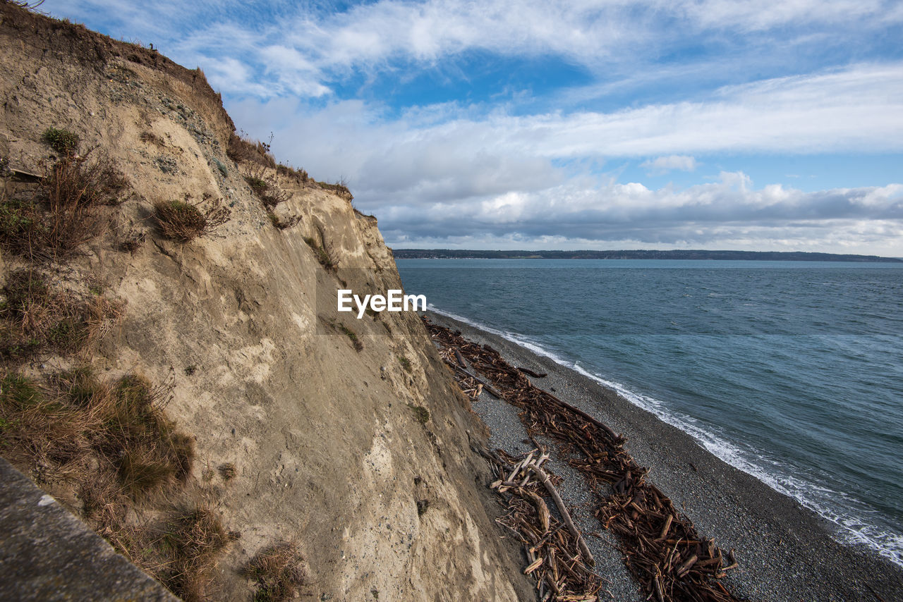 Scenic view of cliff, sea against sky