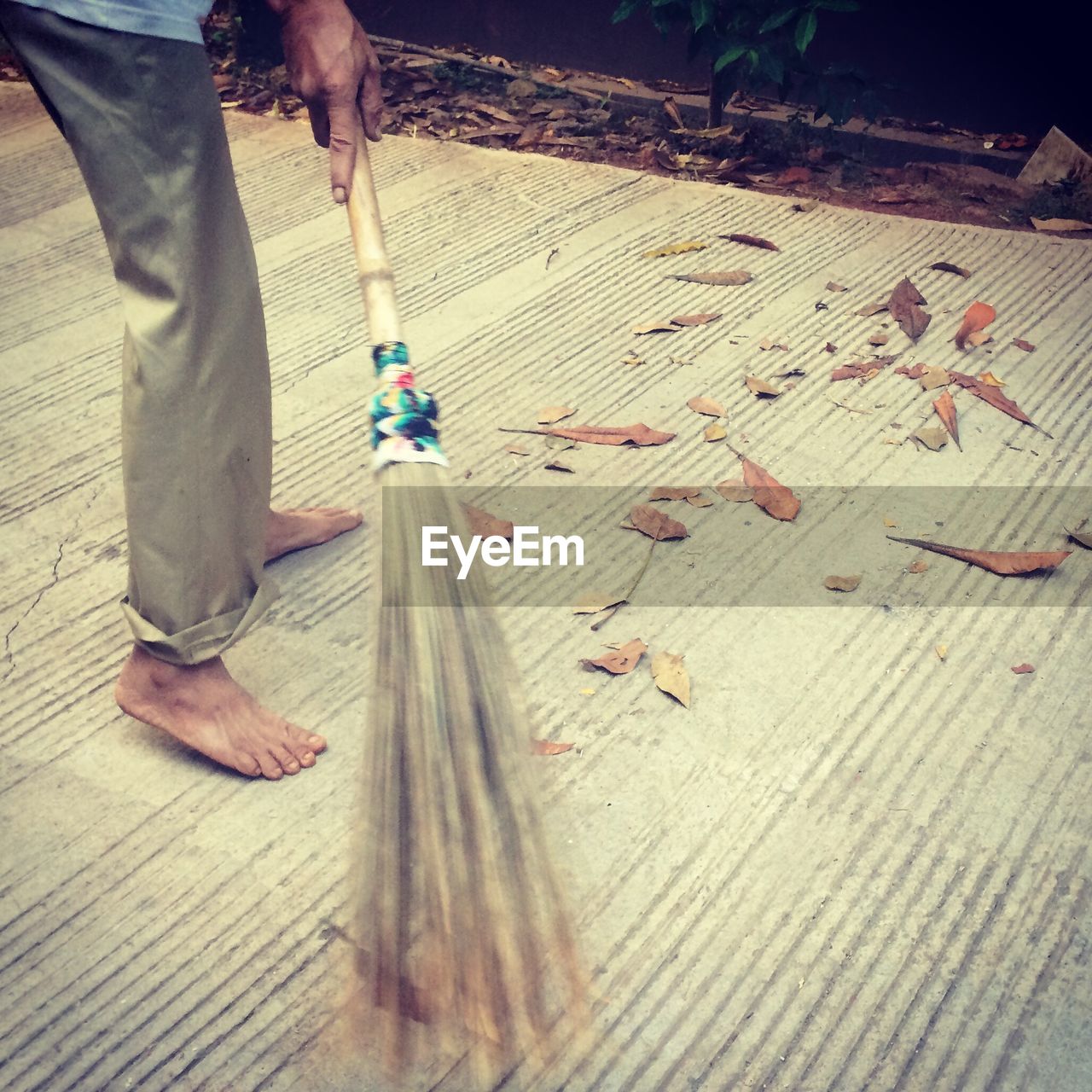 Low section of man sweeping street