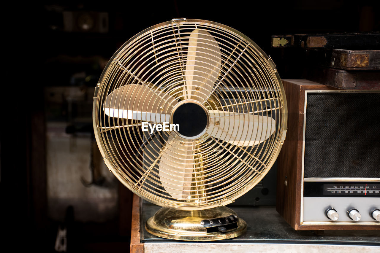 Close-up of electric fan and vintage radio on table