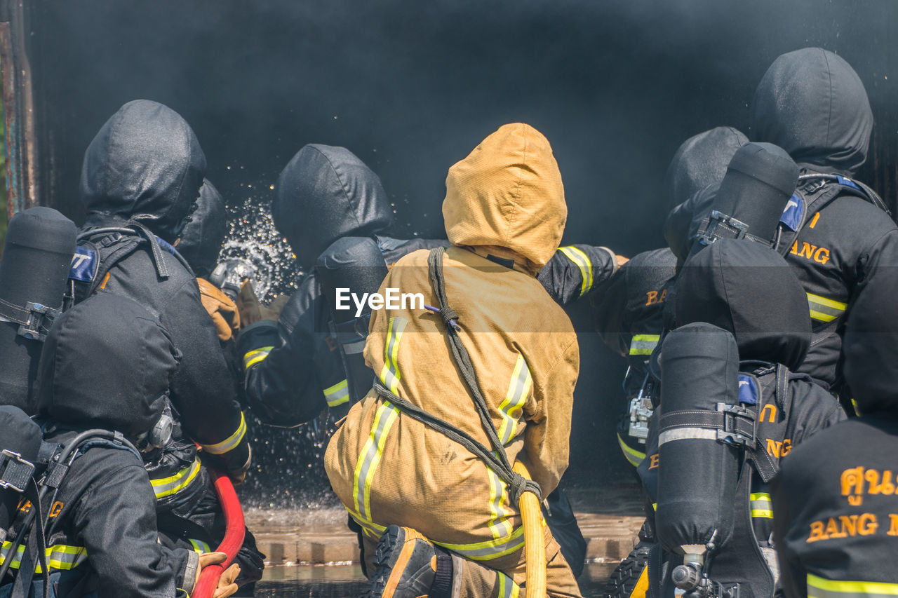 Rear view of firefighters extinguishing fire