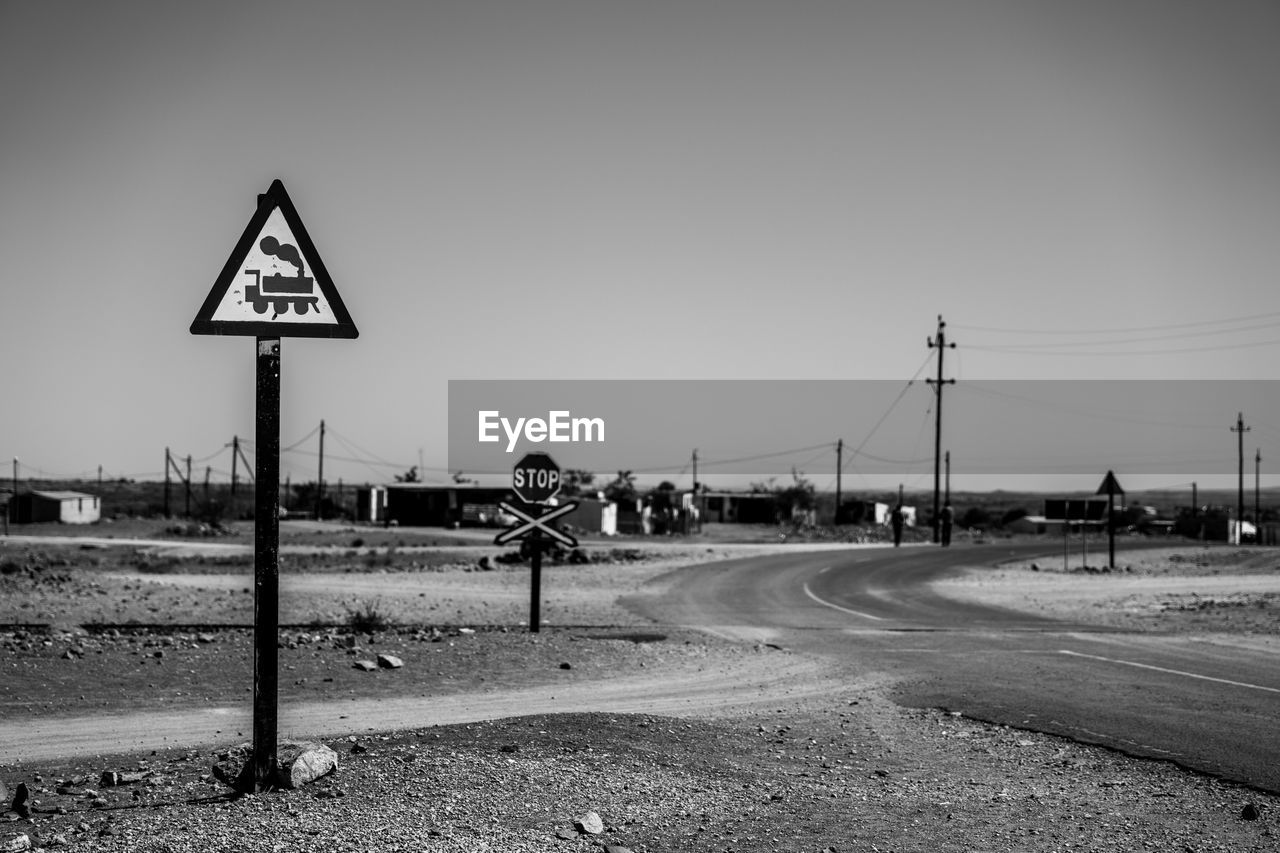 Road sign by street against sky