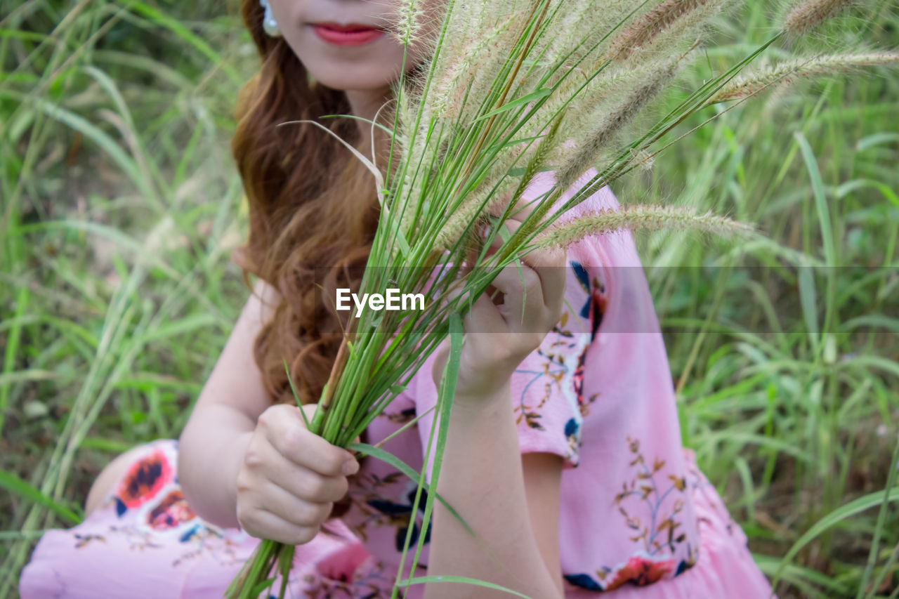 A beautiful woman sitting in the grass in the middle of a field.