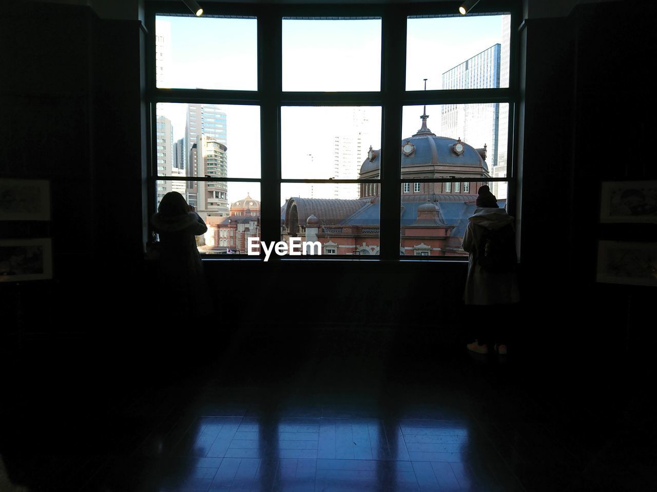 SILHOUETTE MAN STANDING BY WINDOW IN OFFICE BUILDING