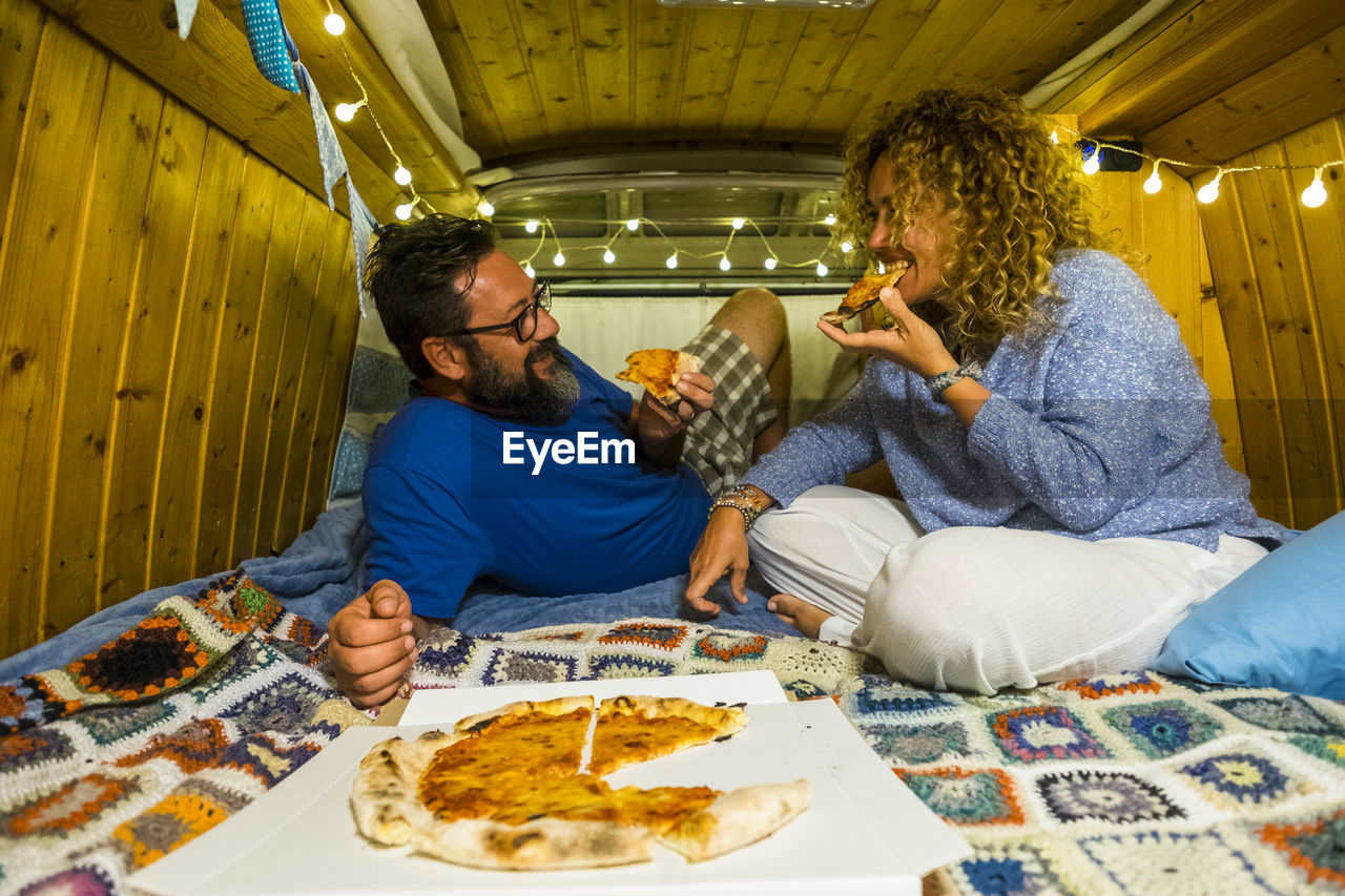 Couple enjoying pizza in illuminated room