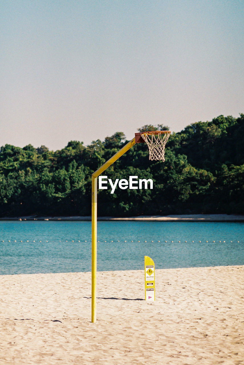 Basketball hoop on beach against clear sky