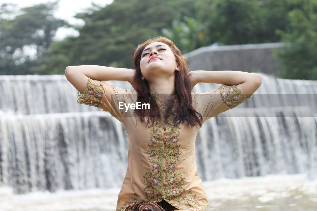 Low section of young woman standing in front of water