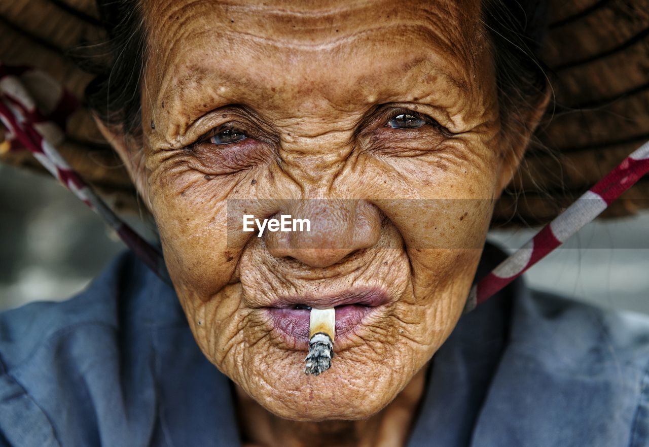 Close-up portrait of senior woman smoking cigarette