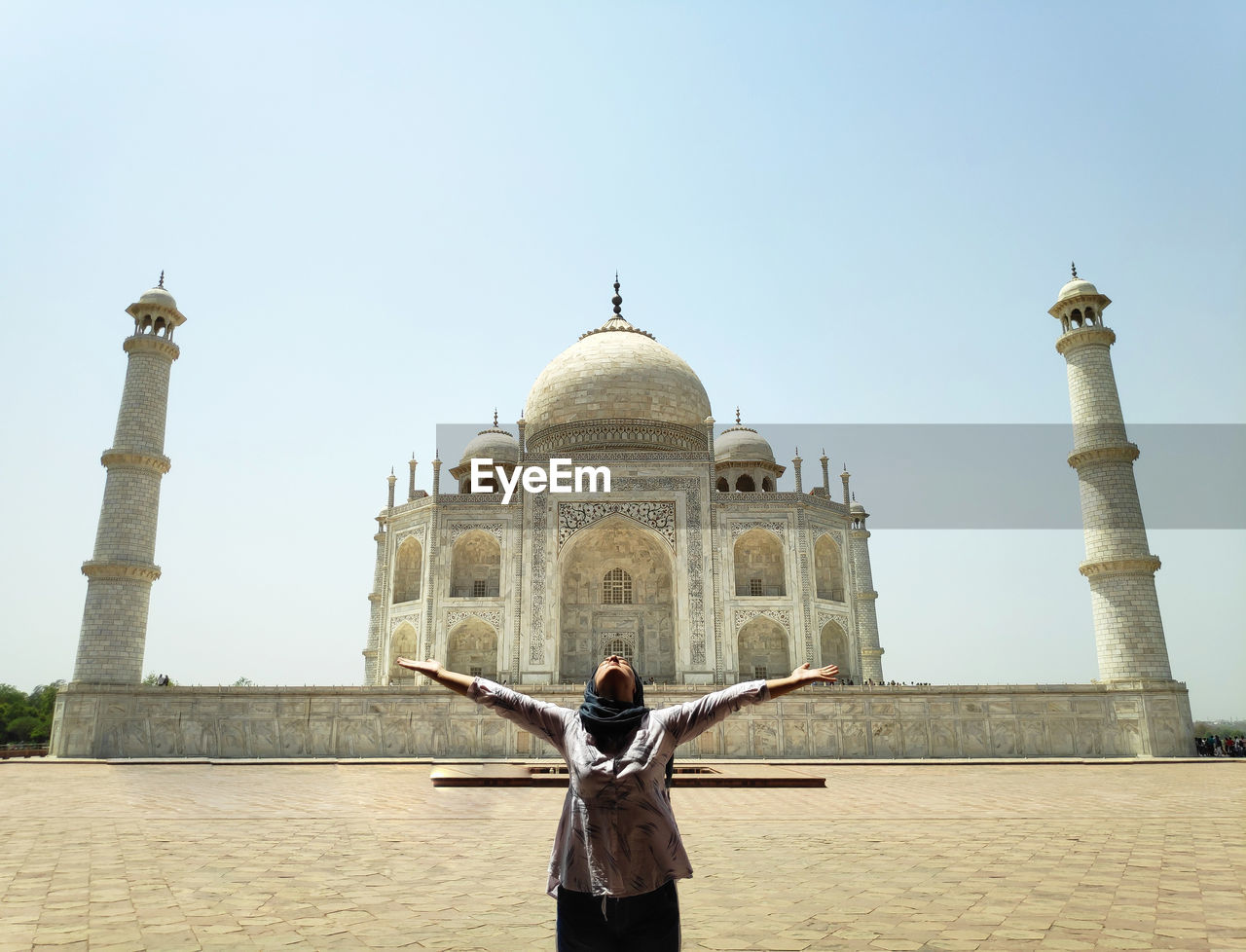 Woman with arms outstretched standing against taj mahal