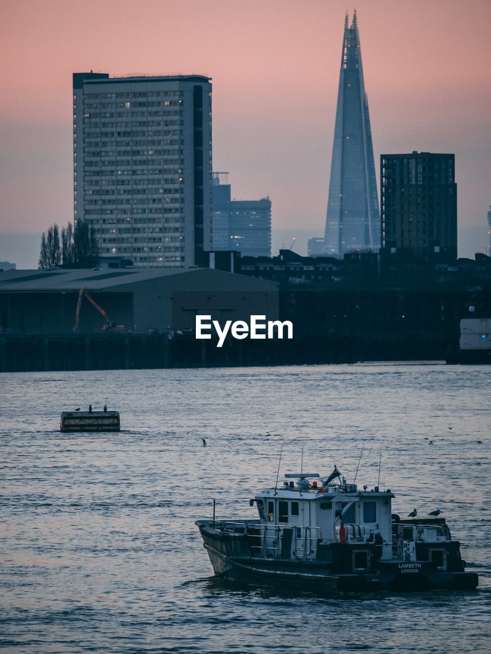 SAILBOATS IN SEA AGAINST MODERN BUILDINGS