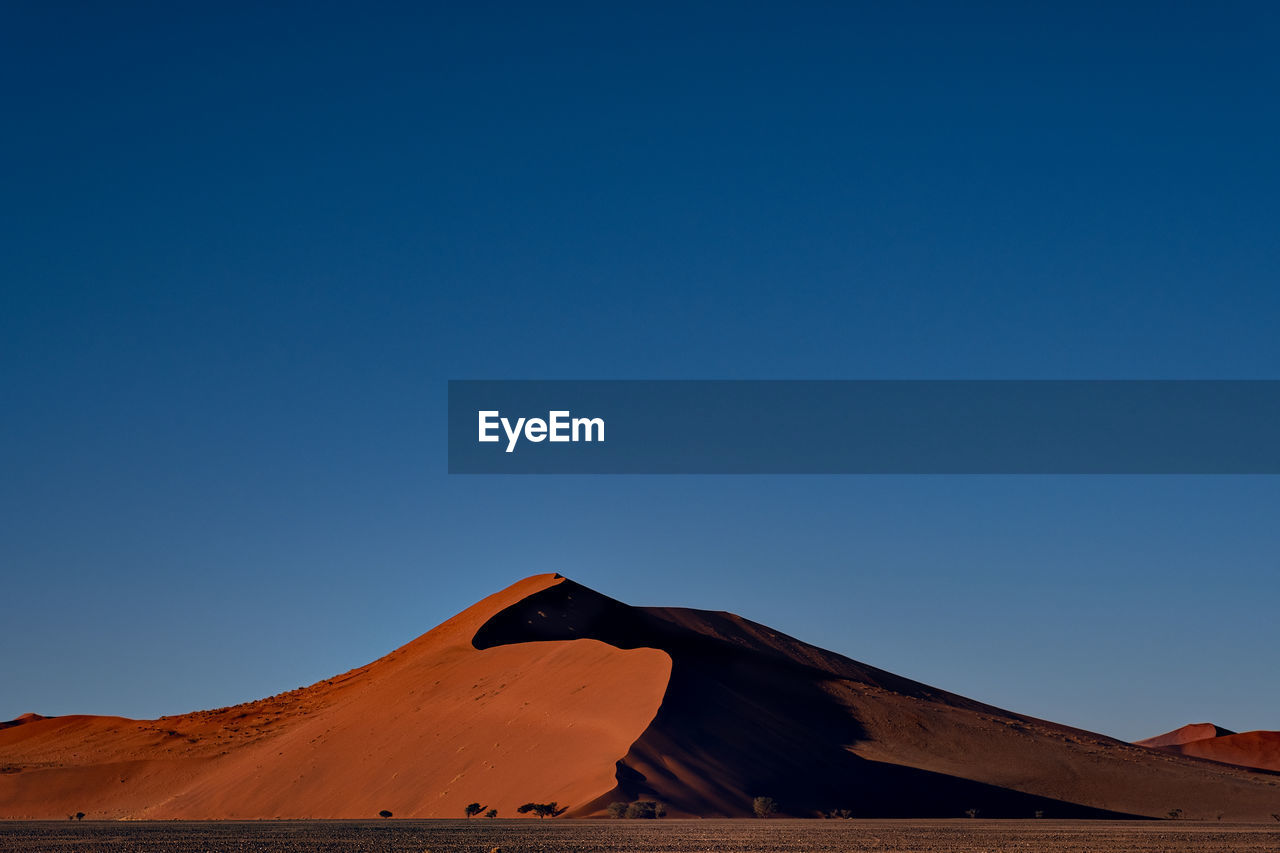 Scenic view of desert against clear blue sky