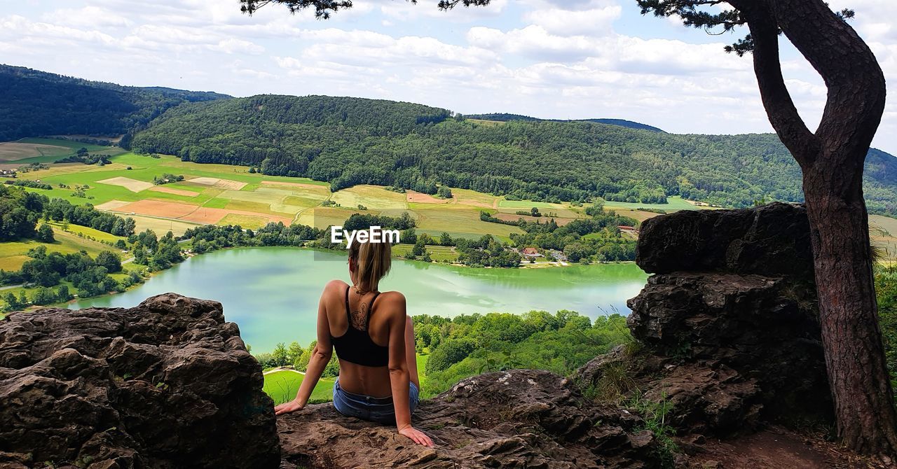 Rear view of woman looking at view of landscape against sky