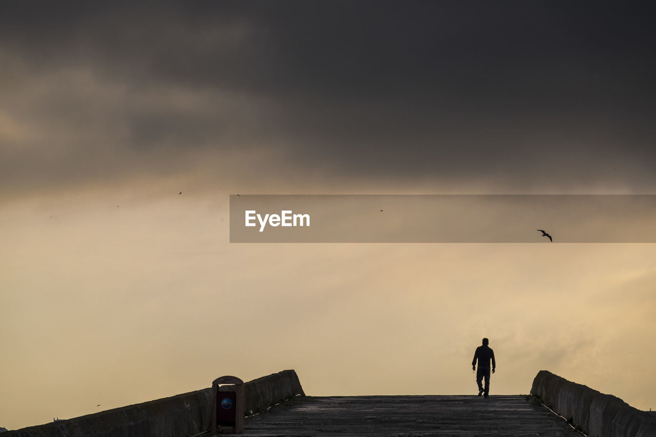 Silhouette people standing on bridge against sky during sunset