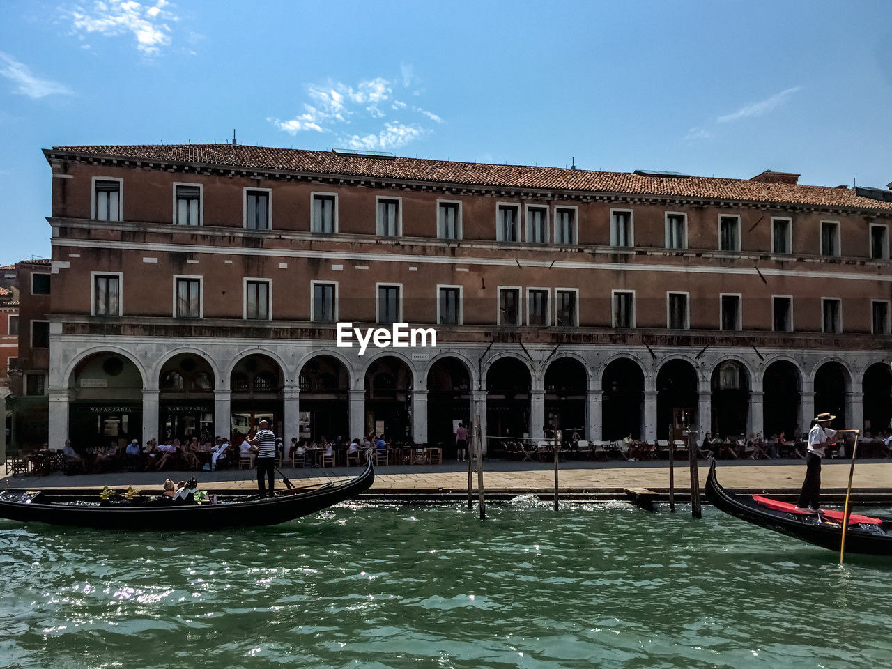 gondola, nautical vessel, water, transportation, mode of transportation, architecture, canal, travel destinations, travel, tourism, building exterior, nature, gondolier, boat, built structure, vehicle, sky, trip, vacation, holiday, tourist, watercraft, city, waterway, arch, group of people, waterfront, outdoors, bridge, day, sea, history, blue, lagoon