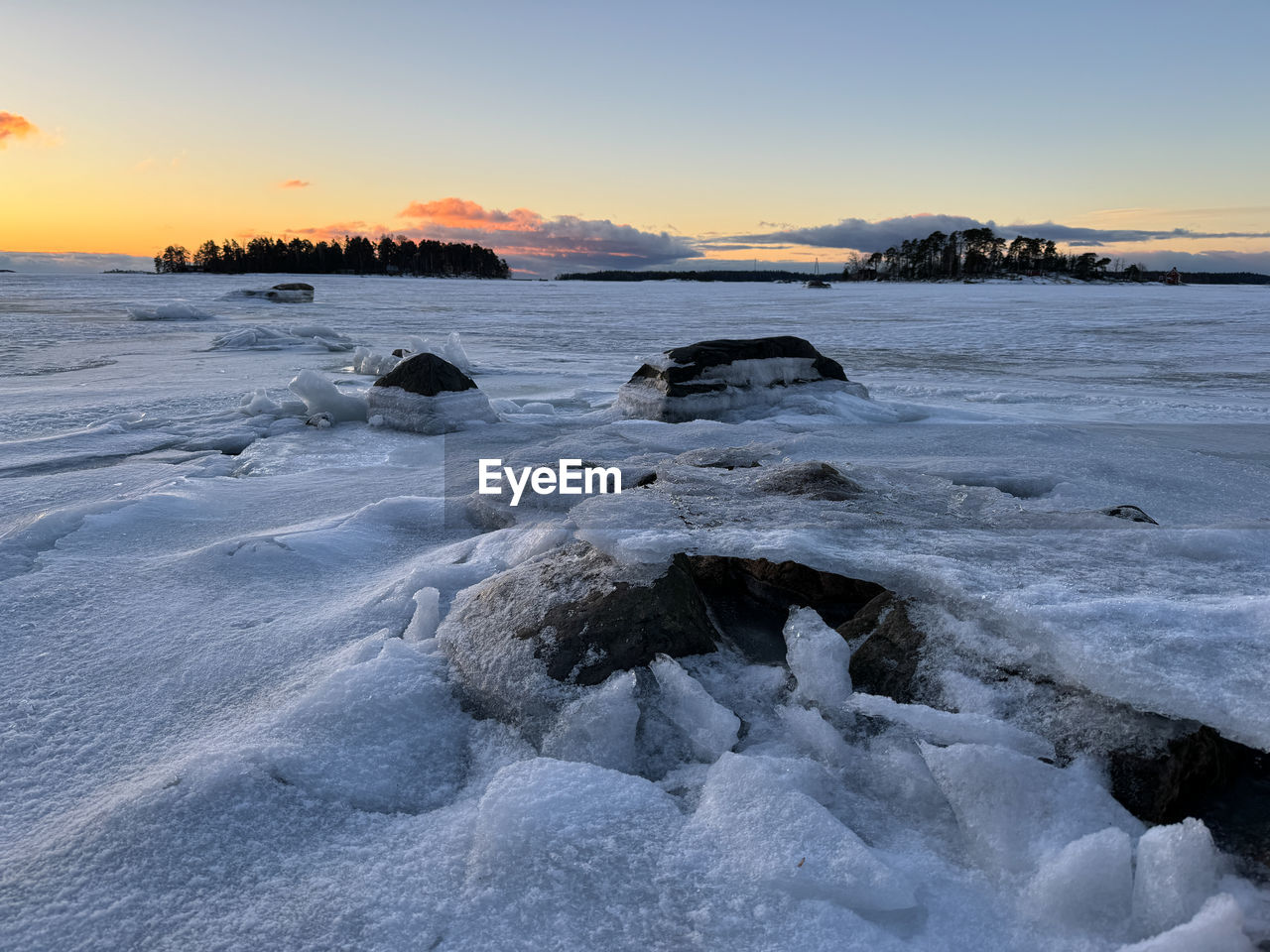 sky, winter, sunset, water, ice, scenics - nature, sea, beauty in nature, landscape, nature, environment, cold temperature, wave, ocean, snow, shore, land, wind wave, coast, tranquility, frozen, travel destinations, sun, rock, cloud, beach, no people, freezing, tranquil scene, travel, body of water, outdoors, dusk, clear sky, blue, non-urban scene, idyllic, twilight, tourism, reflection, mountain, lagoon, sunlight, polar climate, horizon