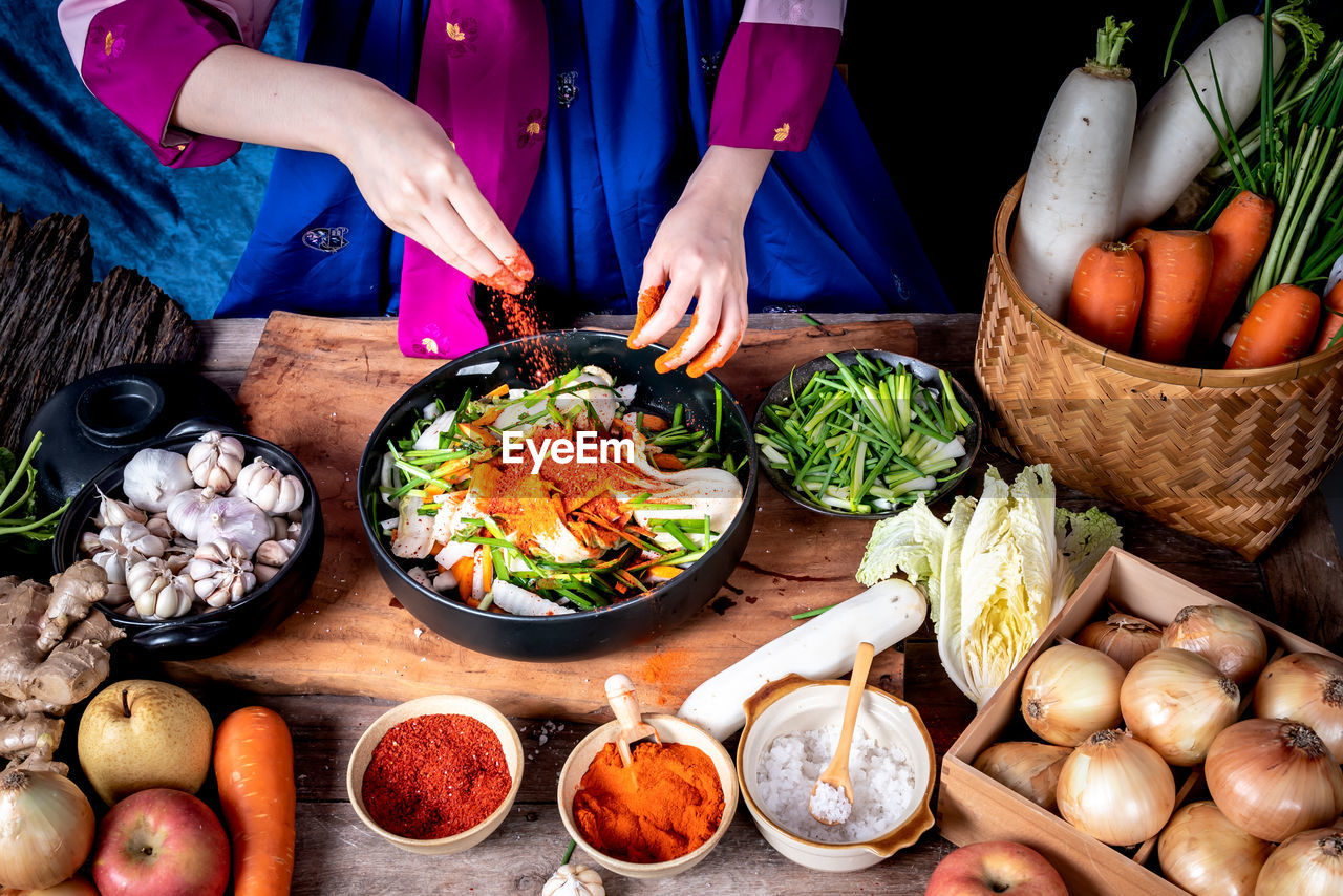 Korean woman is wearing a traditional hanbok, she making kimchi which is a fermented food 