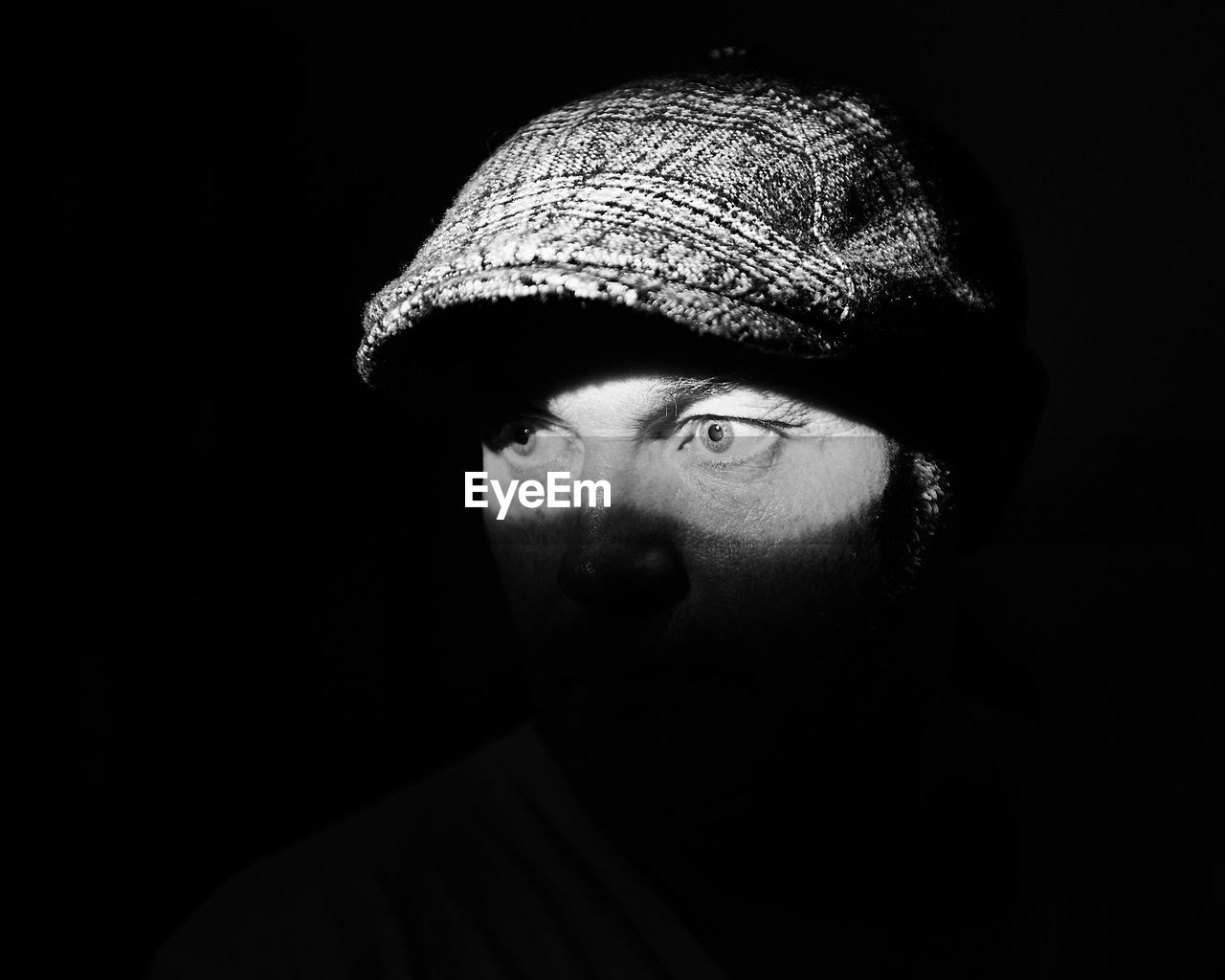 Close-up of thoughtful man wearing flat cap in darkroom