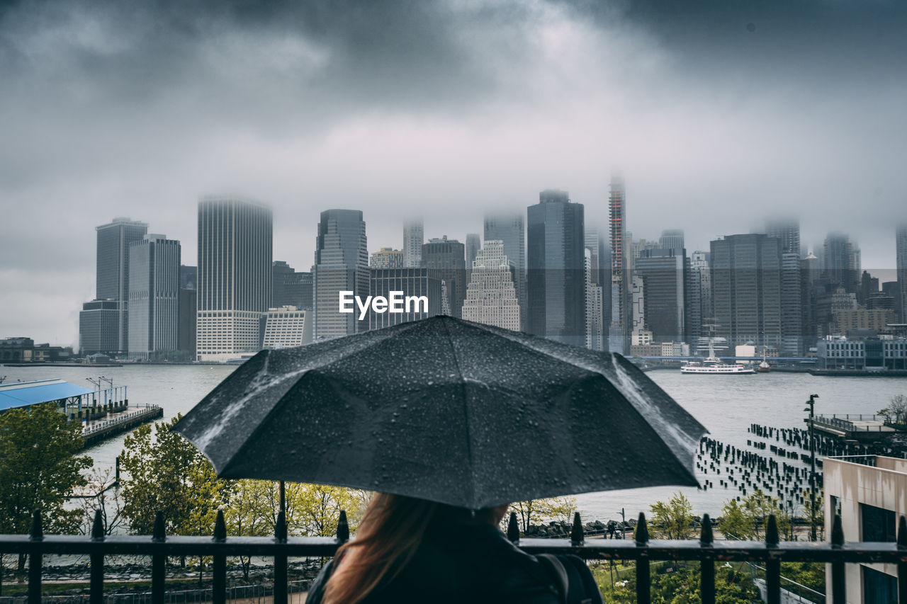 Woman holding umbrella while enjoying view of cityscape