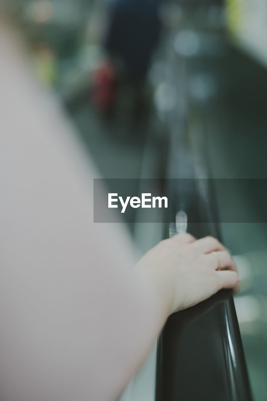 Close-up of woman hand standing on escalator