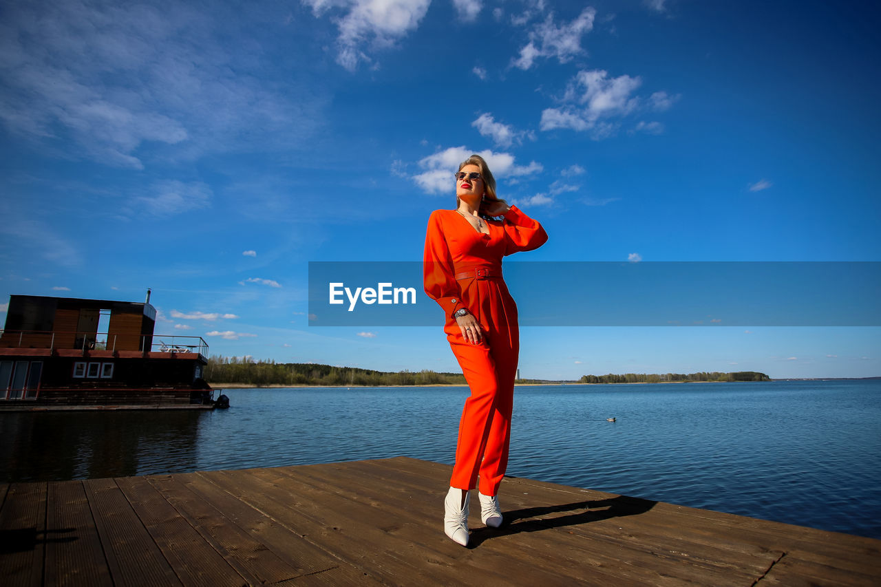 Full length of woman standing against blue sky