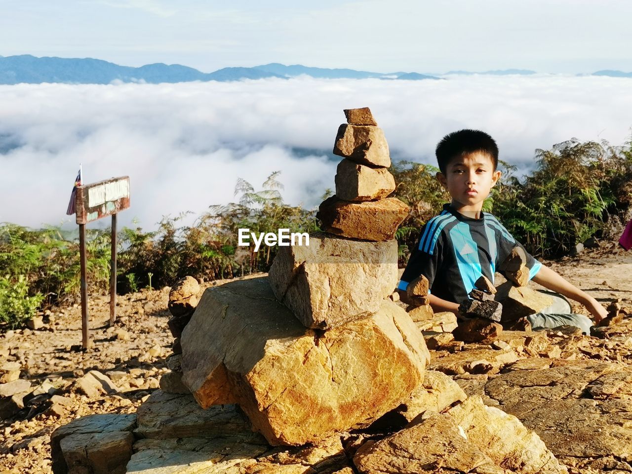 Portrait of boy holding rocks while sitting on land