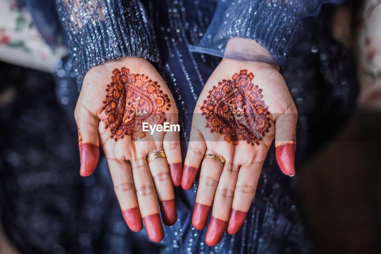 Midsection of woman showing henna tattoo on hands