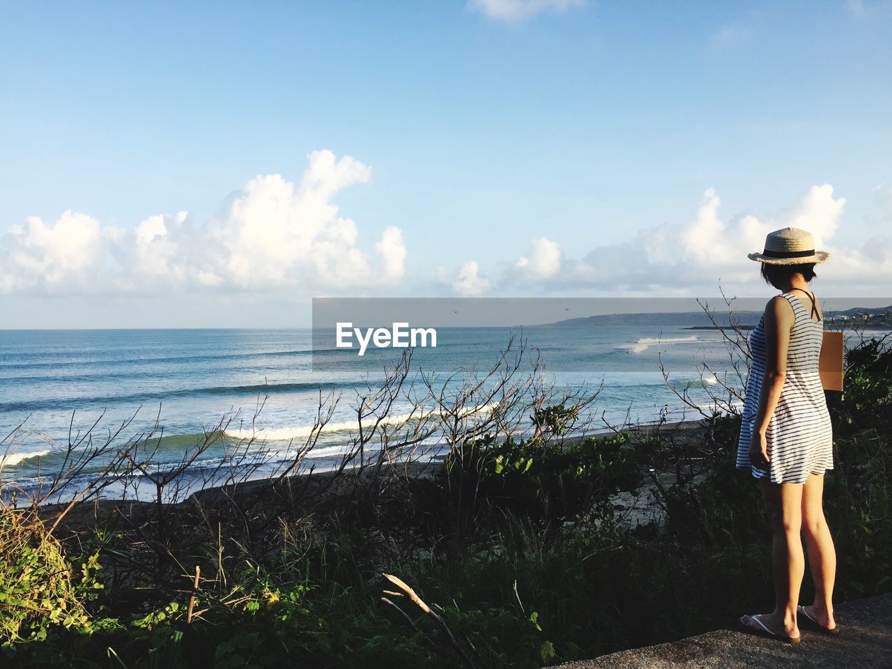 Woman standing at beach against sky