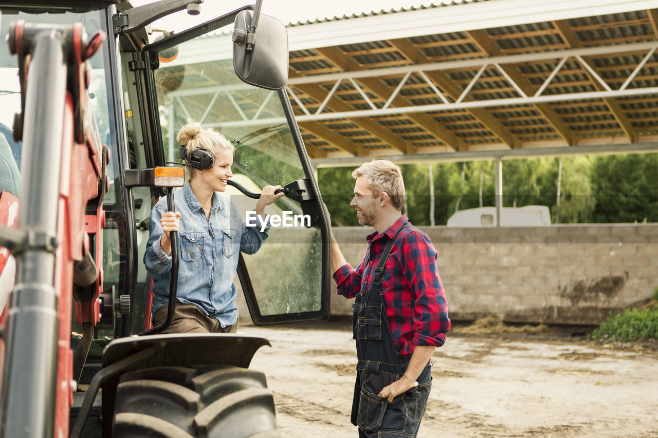 Couple communicating by tractor at farm