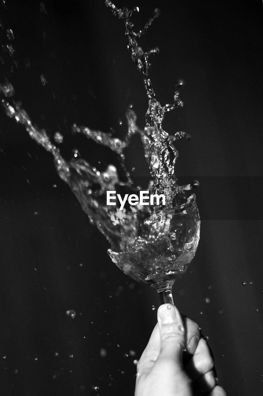 Close-up of hand splashing water against black background