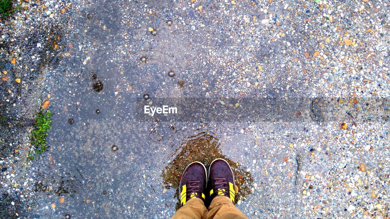 LOW SECTION OF MAN STANDING BY WATER ON GROUND