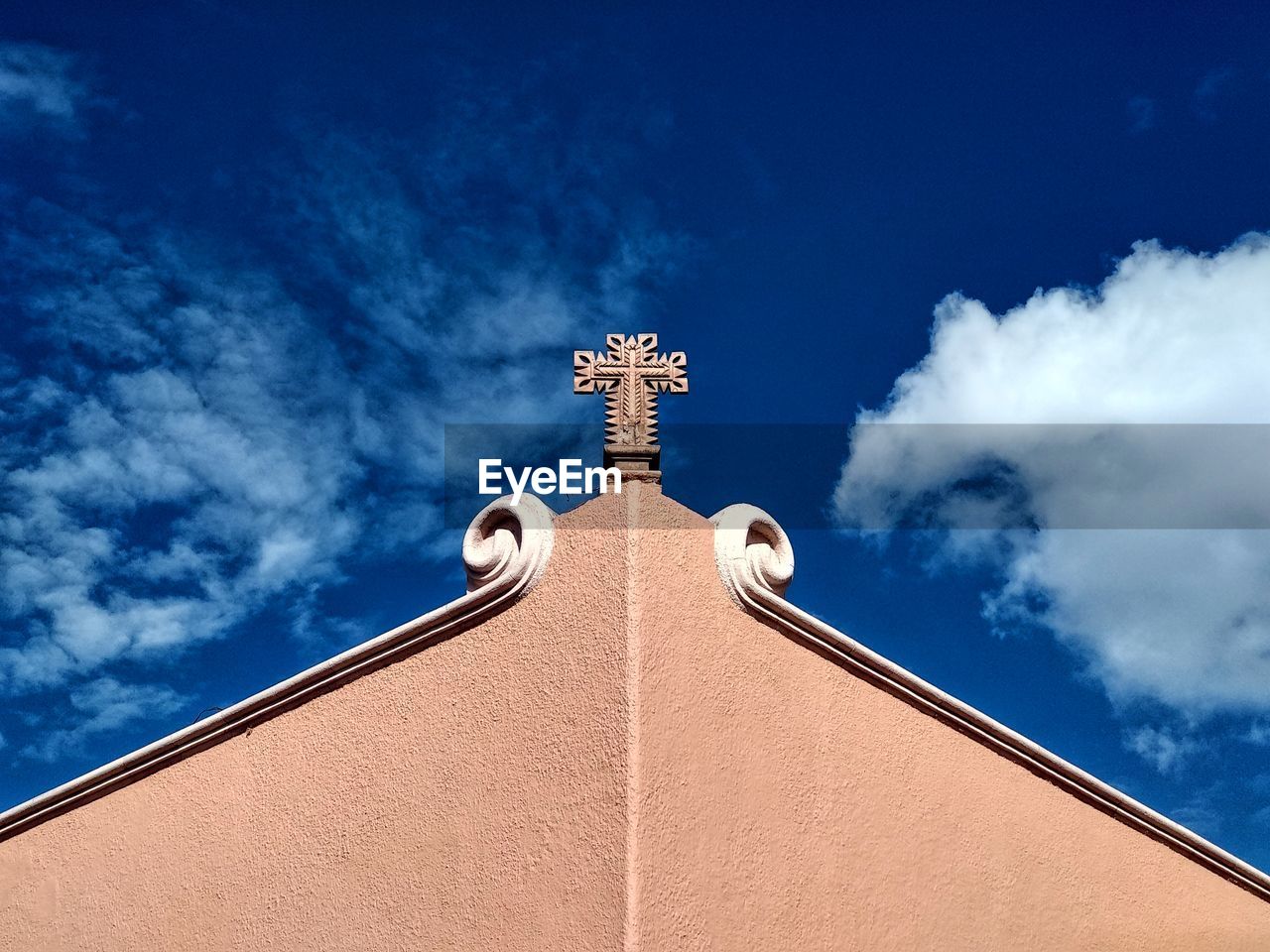 Low angle view of cross and building against blue sky