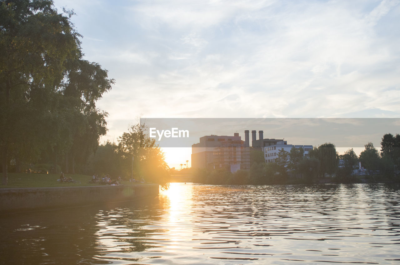 SUNSET OVER RIVER WITH BUILDINGS IN BACKGROUND