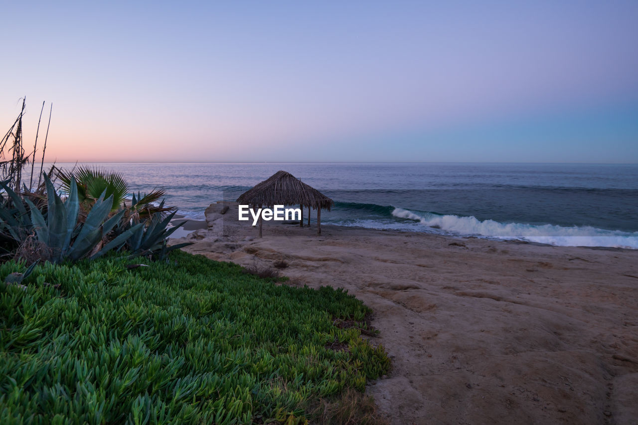 scenic view of beach against clear sky during sunset