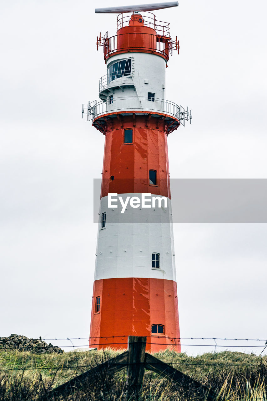 LOW ANGLE VIEW OF LIGHTHOUSE AMIDST BUILDING AGAINST SKY