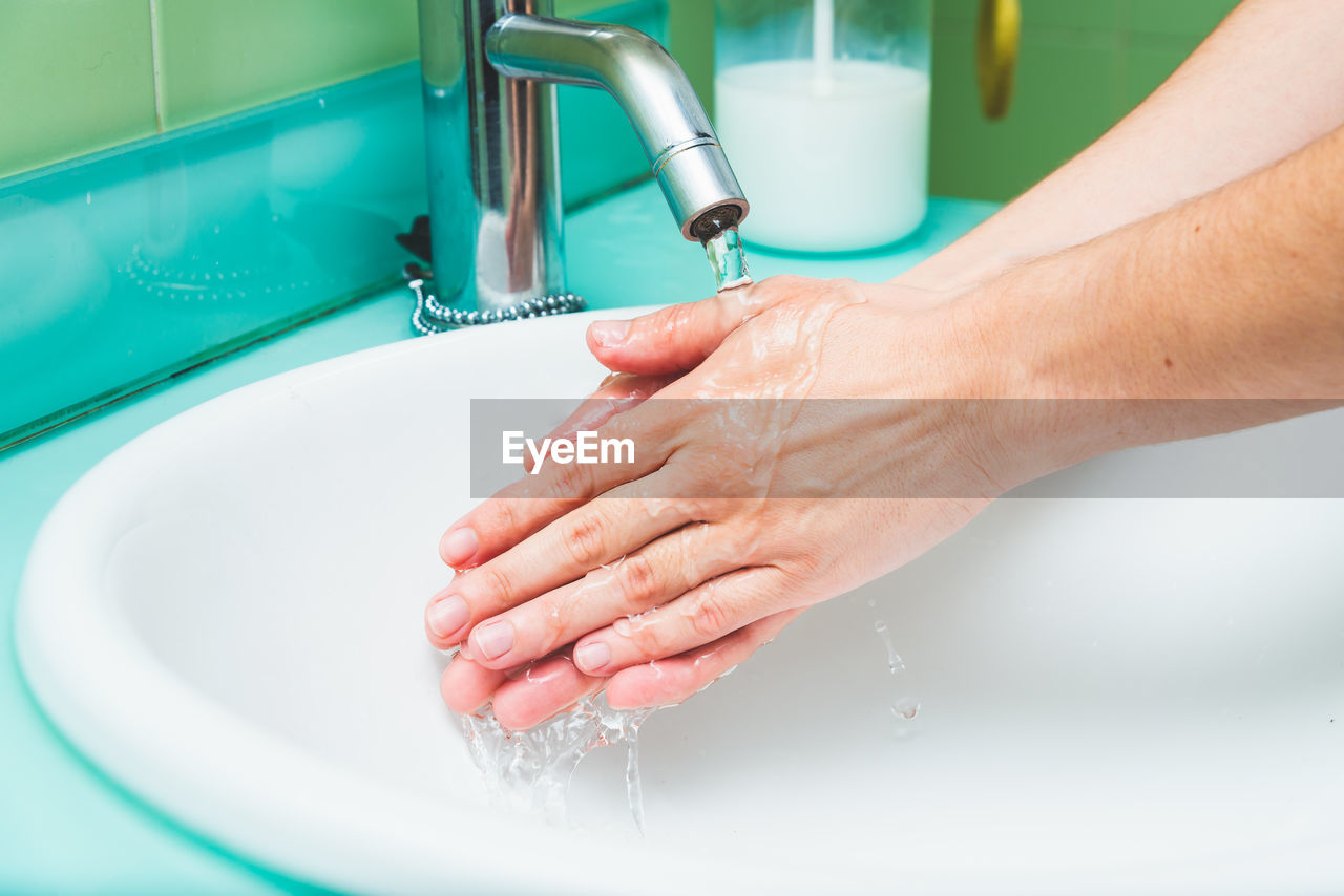 Cropped image of person washing hands in sink