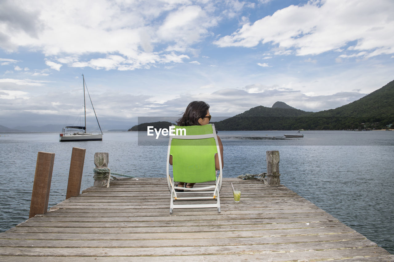 Woman relaxing on pier on the tropical island of ilha grande