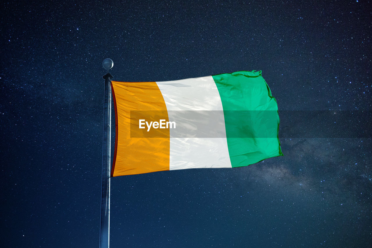 Low angle view of ivorian flag against star field sky