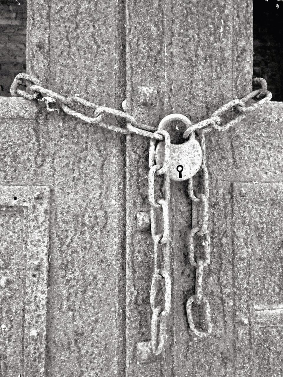 Close-up of rusty lock and chain tied up on door
