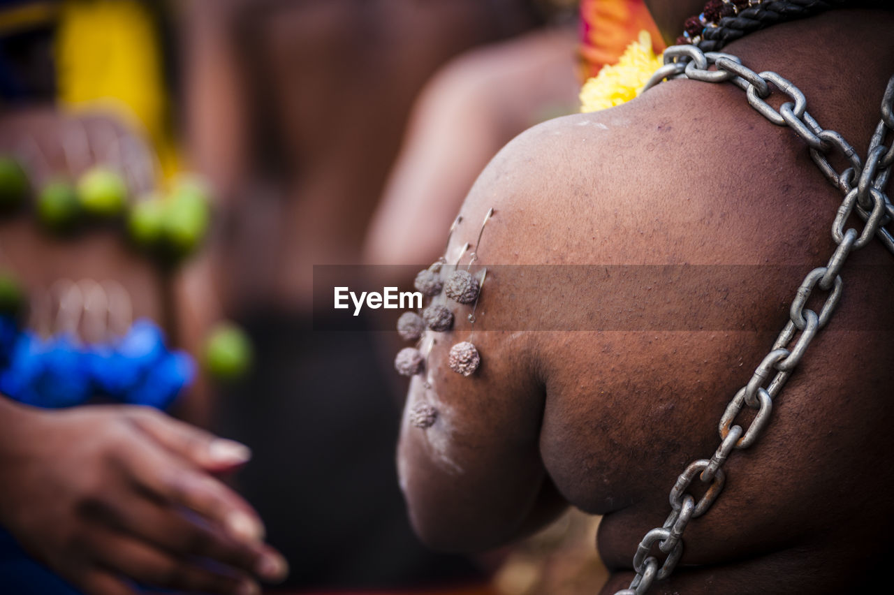 Rear view of man with chains and pierced metal during thaipusam festival