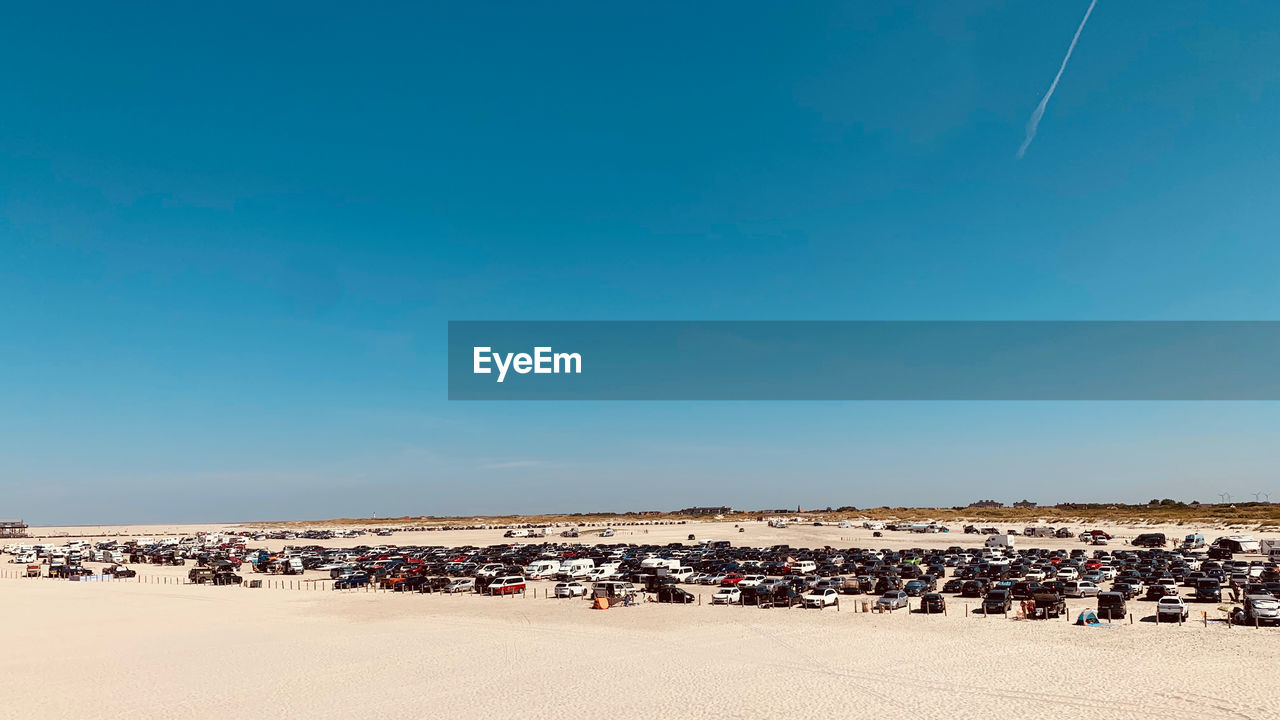 People on beach against clear blue sky