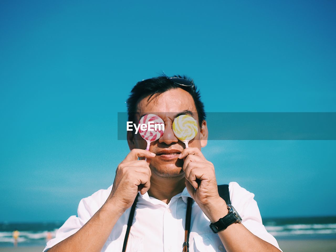 Man holding candies while standing at beach against sky