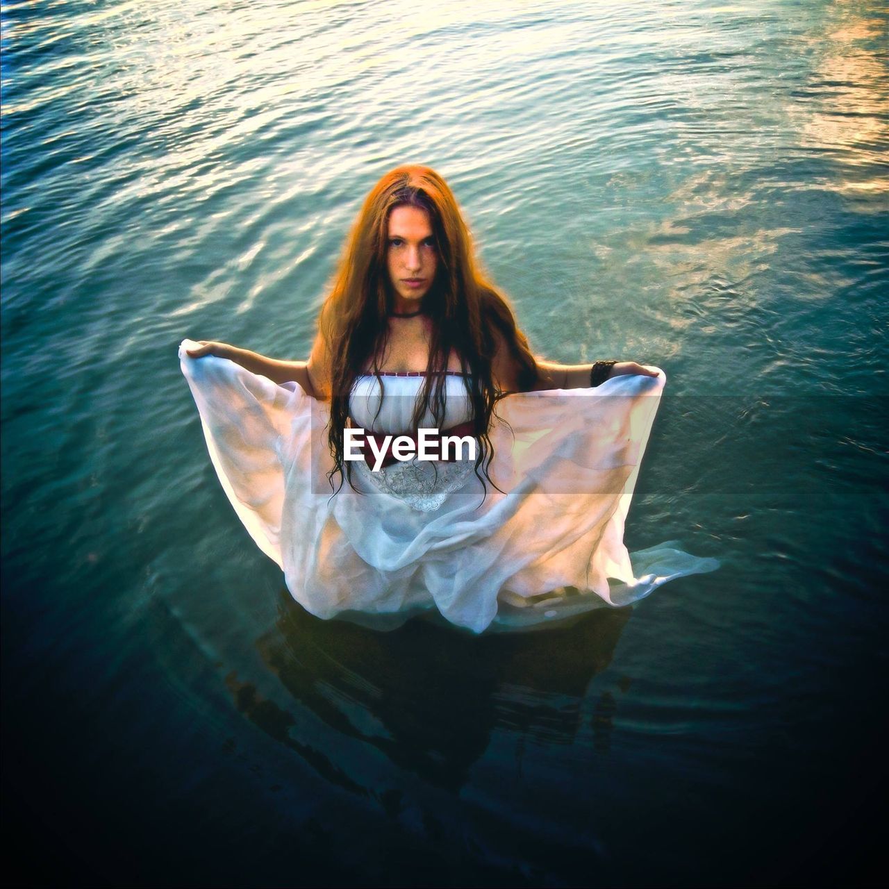 High angle portrait of young woman wearing white dress while standing in lake