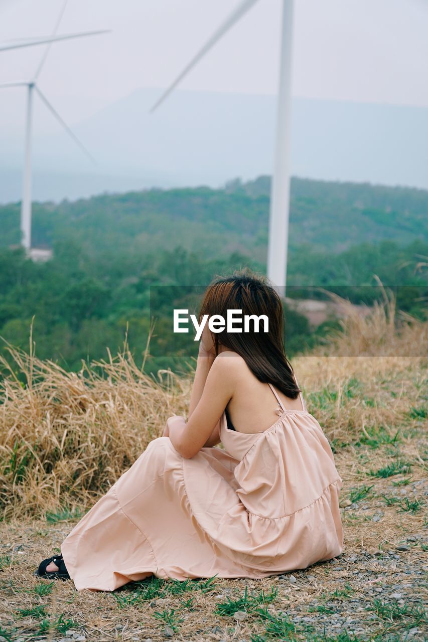 Rear view of woman sitting on field