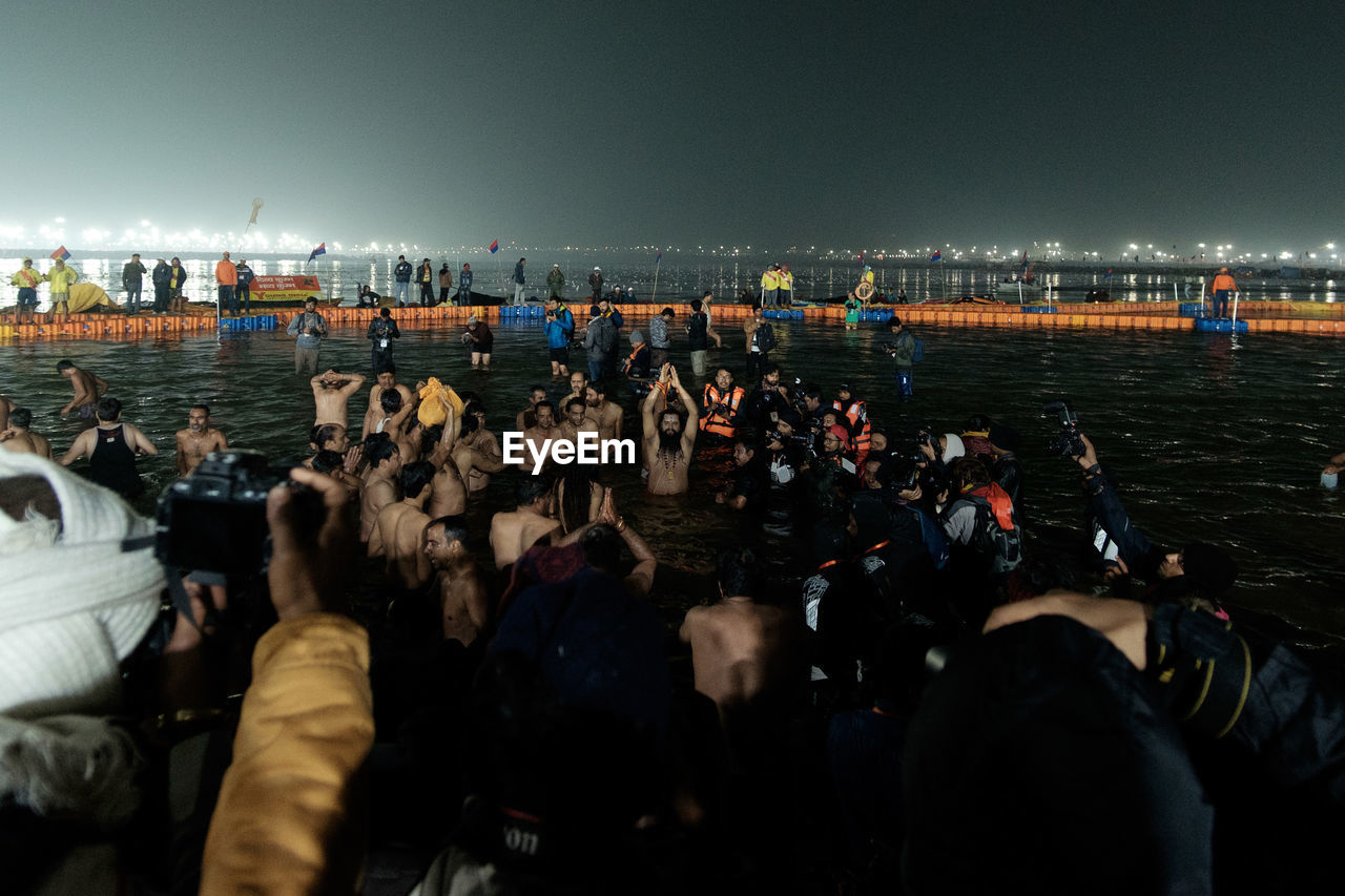 GROUP OF PEOPLE AT BEACH AGAINST SKY